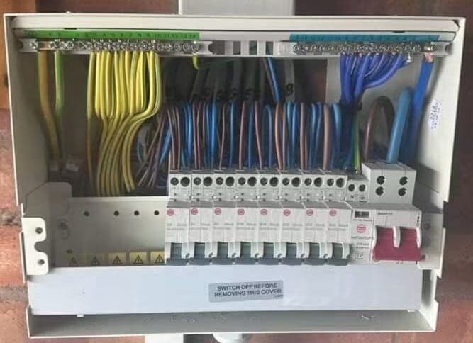 New consumer unit with the cover off, showing neatly dressed cables and a row of breakers